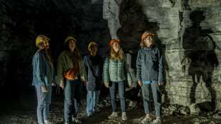 Fünf Freudinnen tragen gelbe und orange Helme. Sie stehen in einem ehemaligen Gipsstollen.