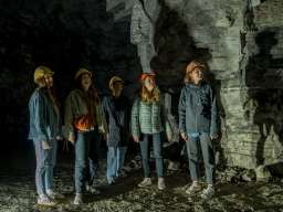 Fünf Freudinnen tragen gelbe und orange Helme. Sie stehen in einem ehemaligen Gipsstollen.