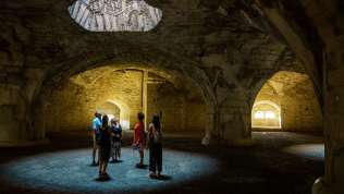 Eine Gruppe mit Guide steht in der Kassematte des Munots. Licht fällt durch Lichtschächte und Formt Kreise am Boden.